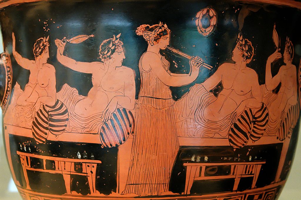 Red-figure krater depicting an ancient Greek symposium (feast) scene, circa 420 BCE. Participants are enjoying the kottabos game while a girl plays the aulos. Painted by the Nikias Painter.