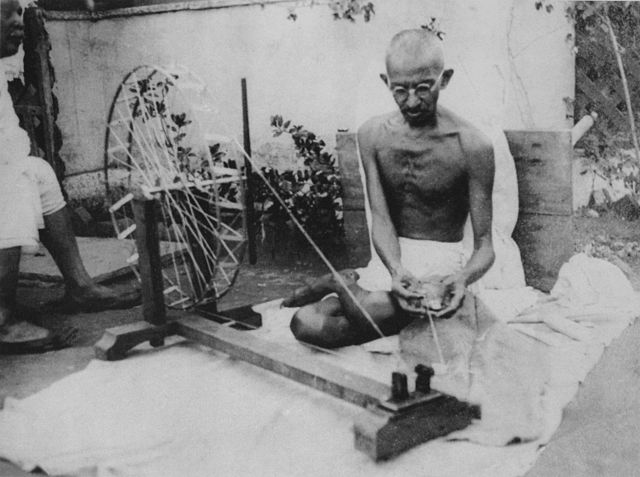 Mahatma Gandhi mengoperasikan charkha. Roda pemintal sederhana ini menjadi simbol gerakan kemerdekaan India.