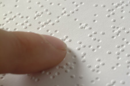 Primer plano de texto en Braille. La disposición de puntos en relieve se puede sentir con los dedos.