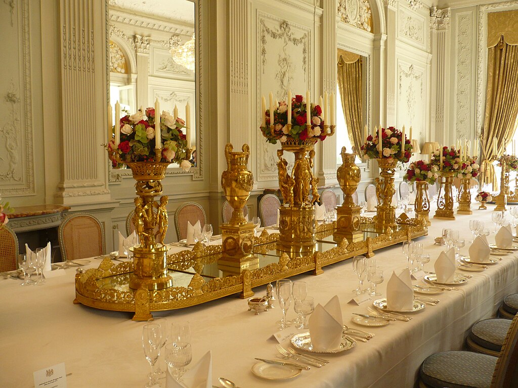 Una gran mesa de comedor dispuesta con vajilla y decoraciones lujosas